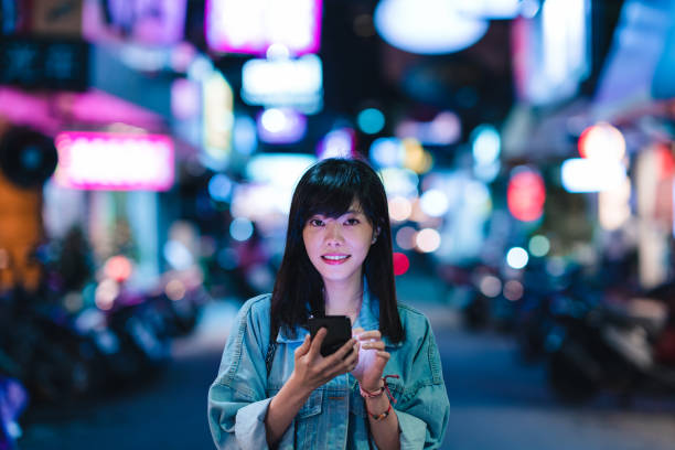 istock A young woman using her phone in the city at night 1149085362