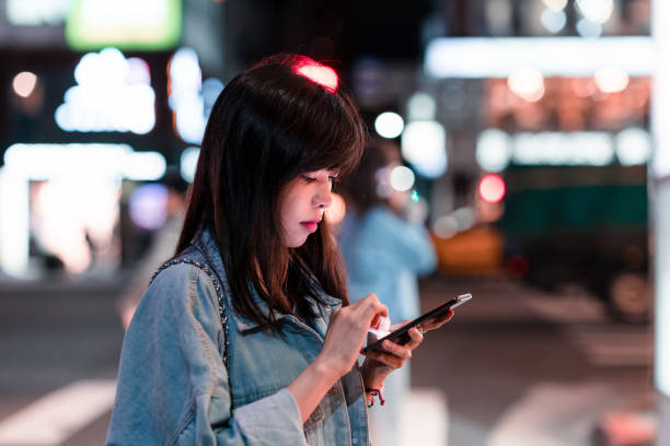 istock A young woman using her phone in the city at night 1149085368