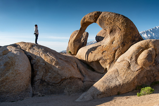 Asian man tourist looking through the mobius arch stone at Alabama Hills, Lone pine, USA. Travel natural attraction concept