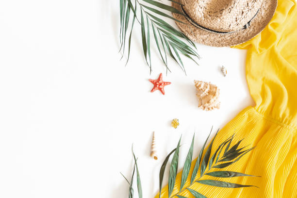 Summer composition. Tropical leaves, dress, hat on white background. Summer concept. Flat lay, top view, copy space