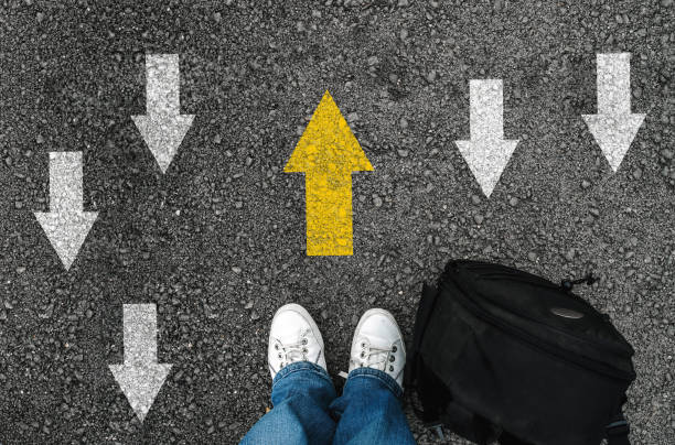 istock man shoes and backpack on asphalt and opposing direction arrows on asphalt ground 1149086701