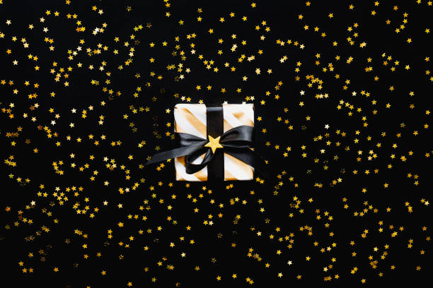 istock Gift box over star shaped golden sequins on a black background. 1149087700