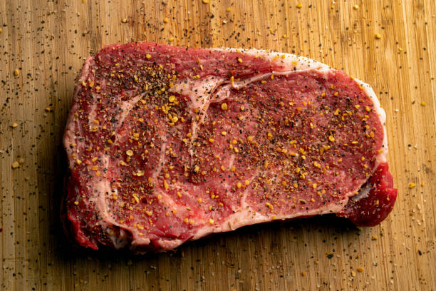 乾燥させる準備ができたまな板の上で味付けした生のリブアイステーキ - rib eye steak beef cutting board meat ストックフォトと画像