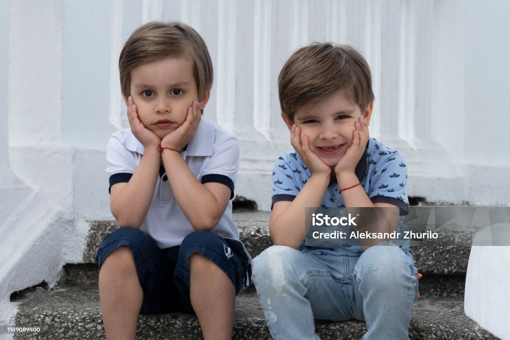 Kindermode. Schöne Zwillingsbrüder in eleganten Klamotten sitzen dicht beieinander - Lizenzfrei Braunes Haar Stock-Foto