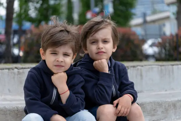 Portrait of fraternal twins on outdoor in stylish clothes. Children's fashion and style