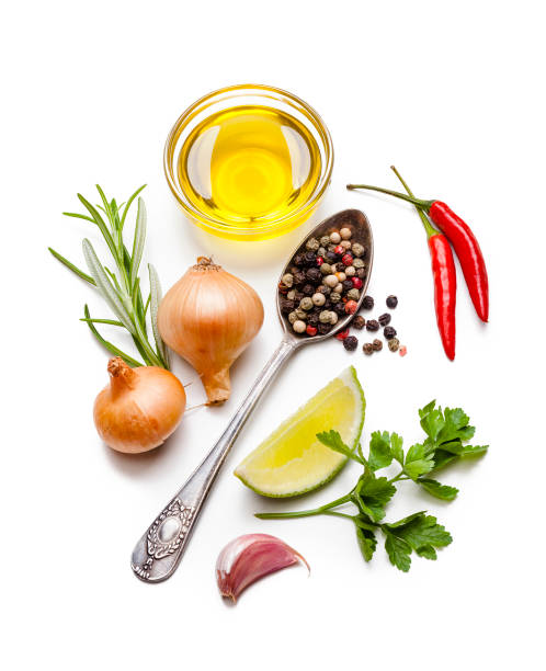 Cooking and seasoning ingredients: olive oil, spices and herbs on white background Cooking and seasoning ingredients: high angle view of olive oil in a small glass bowl, peppercorns in a vintage spoon, lime slice, parsley, chili pepper, garlic clove and a small gold onions isolated on white background. High key DSRL studio photo taken with Canon EOS 5D Mk II and Canon EF 100mm f/2.8L Macro IS USM. pepper seasoning stock pictures, royalty-free photos & images