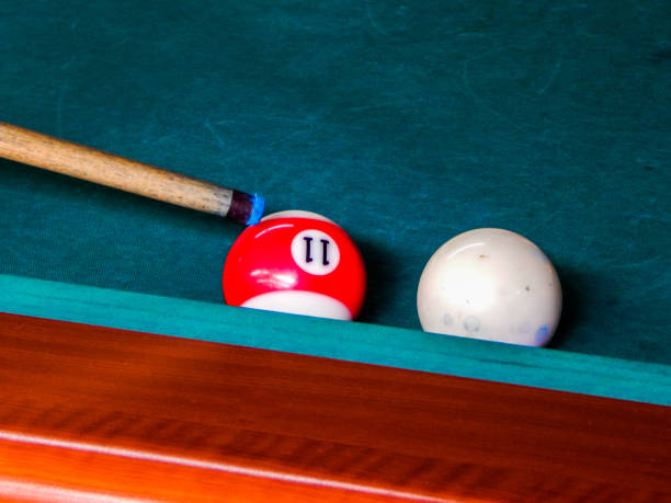 istock One red billiard ball and white ball and a cue on a pool table 1149090399