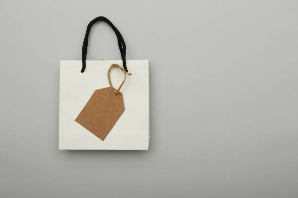 istock White paper bag package on gray background. Place for text. Mock up concept for gift wrapping. 1149094011