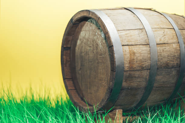 istock Old woden barrel in grass on a yellow background. 1149096195