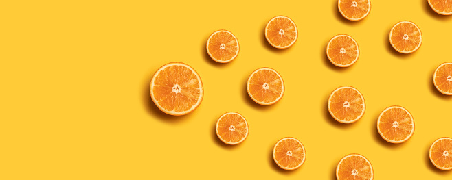 Fruit pattern of fresh orange slices on yellow background.