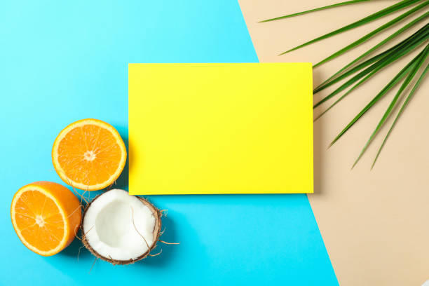istock Oranges, coconut, palm leaves and square with space for text on two tone background. Summer vacation 1149106118