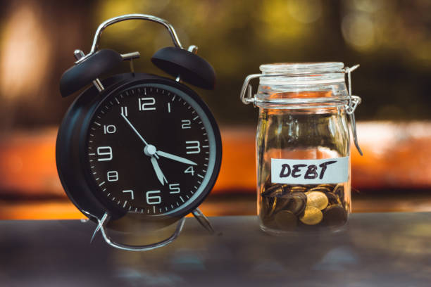 istock Jar with coins and black clock on a table 1149106390
