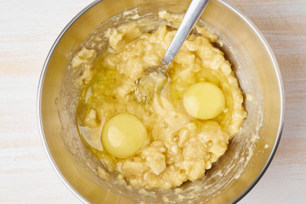 istock Mashed banana with egg. Step by step recipe. Homemade Banana bread. Top view, white wooden table. 1149107247