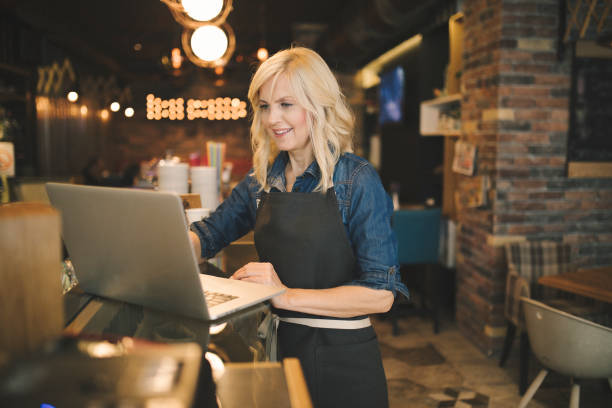 Coffee shop owner working on laptop stock photo