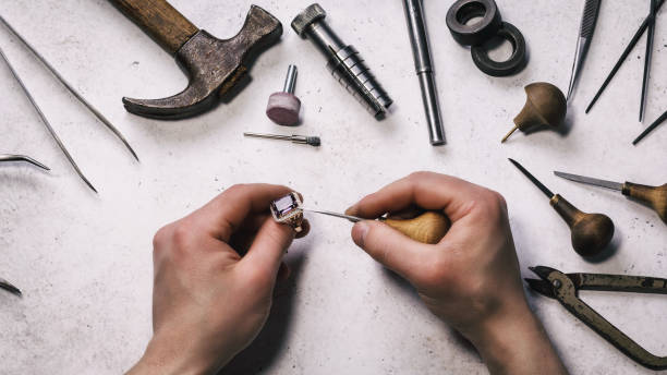 The jeweler checks the strength of fixing a stone in a gold ring, top view The jeweler checks the strength of fixing a stone in a gold ring, top view jewelry craftsperson craft jeweller stock pictures, royalty-free photos & images