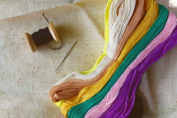 istock multi-colored colorful rainbow colors threads for embroidery floss on light fabric canvas, accessories for sewing and embroidery in sewing shop with free copy space. Concept female craft hobby 1149111899