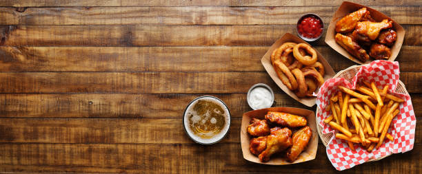 aperitivos pub como asas de frango, anéis de cebola e batatas fritas na composição panorâmica - bar food - fotografias e filmes do acervo