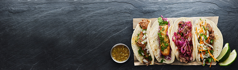 four mexican street tacos with fish barbacoa and carnitas shot in panoramic composition and copy space