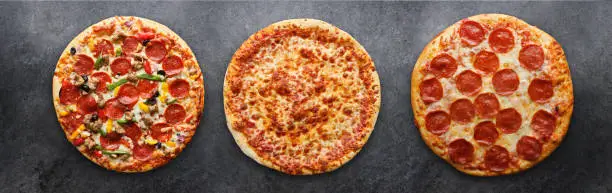 three different pizzas in panoramic composition on dark surface