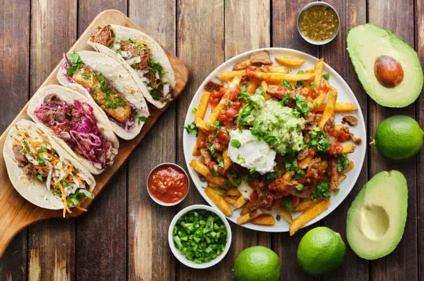 mexican street tacos and carne asada fries in flat lay composition on wooden table