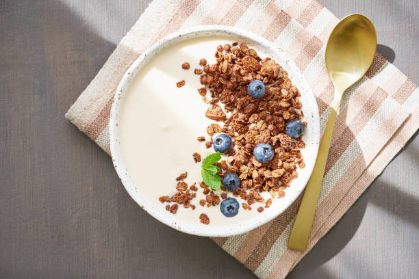 yoghurt med chokladmüsli, blåbär. frukost på ett brunt bord, topp utsikt, solljus - yoghurt chocolate bowl bildbanksfoton och bilder