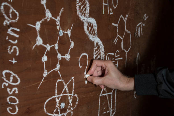 istock A man's hand from darkness writes a question among formulas on an improvised chalkboard 1149115976