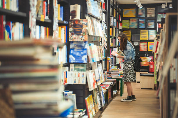 Female student searching for books in the book store (book covers are edited) stock photo