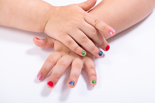 Close-up Small Girl Showing Colorful Nail Polish Against White Background