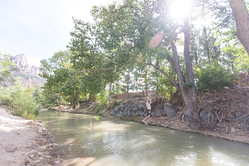 Young male swinging off a rope swing into a river