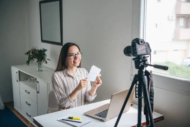 Girl video blogger or online foreign language teacher writes a training video for their subscribers to upload to social networks.