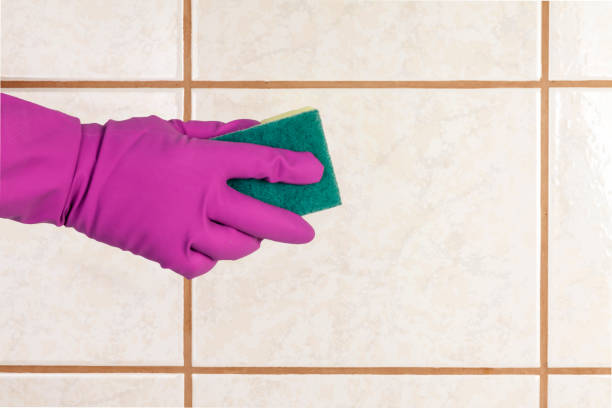 istock A gloved hand holds a sponge and washes ceramic tiles. 1149123302