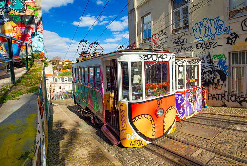 LISBON, PORTUGAL - JULY 4, 2019: The Elevador or Ascensor da Bica is a popular tourist attraction in Chiado District, Lisbon. Tagus river on background.