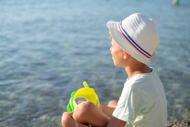 istock Boy sitting alone at the sea coast 1149133122
