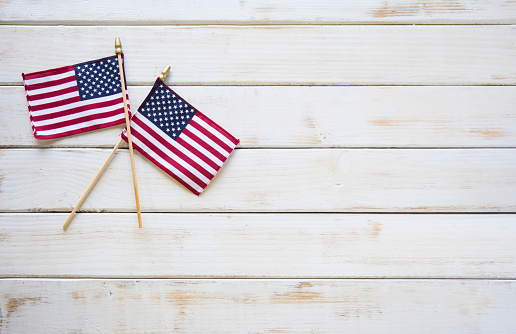 This is a close up photo of two American flags on and old retro white wooden table. This is a great image for memorial day, veterans Day, etc.