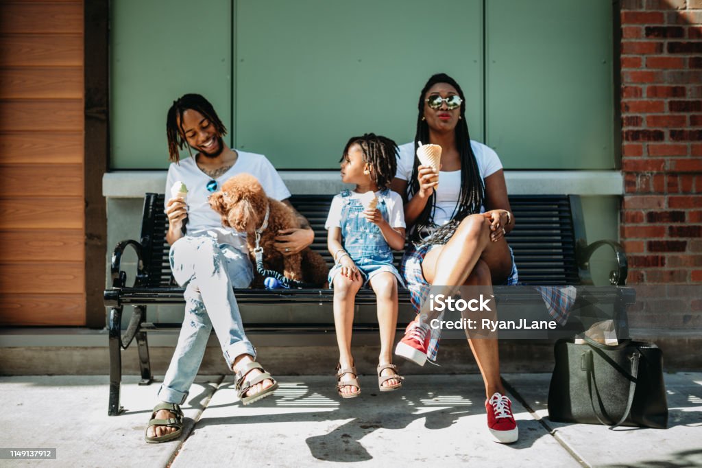 Family Enjoying Ice Cream In City of Tacoma A cute young African American family enjoys relaxation time in the city of Tacoma, Washington with ice cream cones on a hot summer day.  Their dog attempts to eat some ice cream as well. Dog Stock Photo