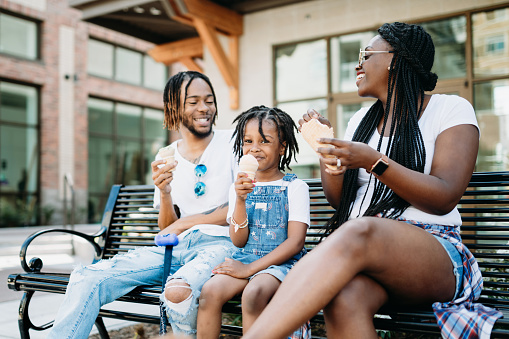 A cute young African American family enjoys relaxation time in the city of Tacoma, Washington with ice cream cones on a hot summer day.