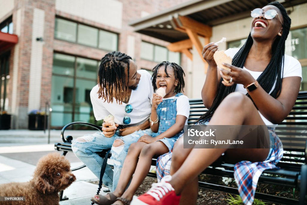 Family Enjoying Ice Cream In City of Tacoma A cute young African American family enjoys relaxation time in the city of Tacoma, Washington with ice cream cones on a hot summer day.  Their poodle dog waits for them to finish. Family Stock Photo