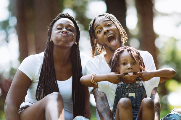 A cute young African American family enjoys relaxation time in a city public park.  They make silly faces for a family portrait . Shot in Tacoma, Washington.