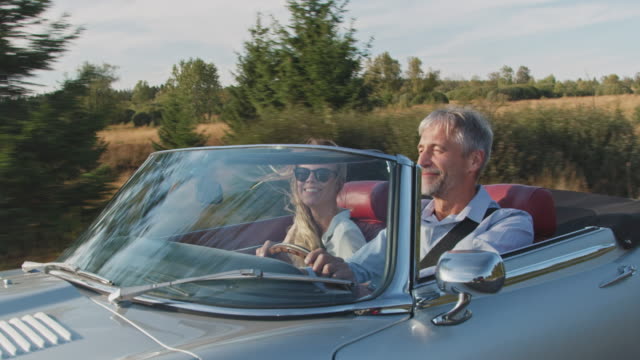 Couple traveling in classic car during windy day