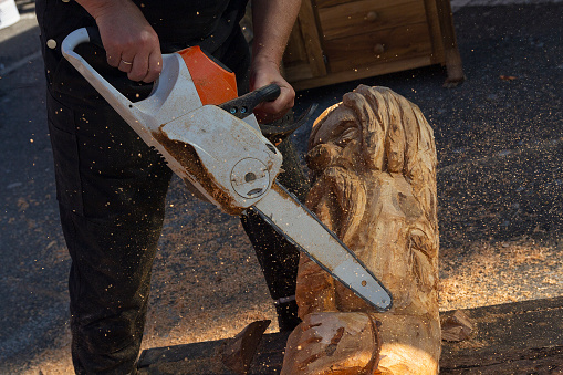 Man with a chainsaw creates a sculpture made of wood. Woodcarving