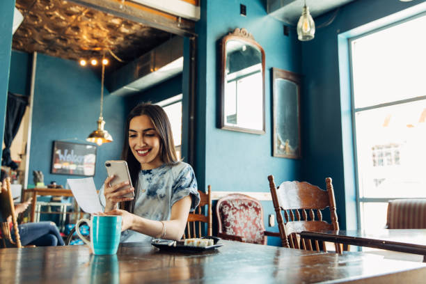 Hispanic Woman Tracking Restaurant Bill A hispanic woman of the Millennial Generation is taking a picture of a restaurant receipt after eating lunch at a local sushi restaurant. The woman is using her phone and bank's app to balance her monthly budget. Image taken in Utah, USA. receipt photos stock pictures, royalty-free photos & images