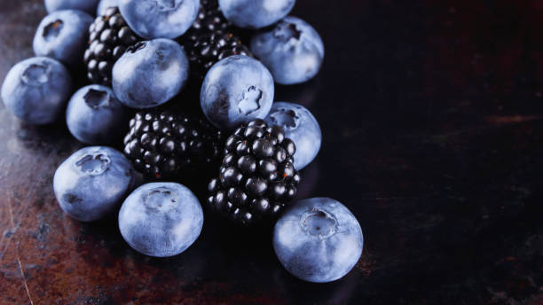 istock Blueberries and blackberries on dark background. Fresh berries for vegan. Assorted berries on rusty background. Flat lay 1149141521
