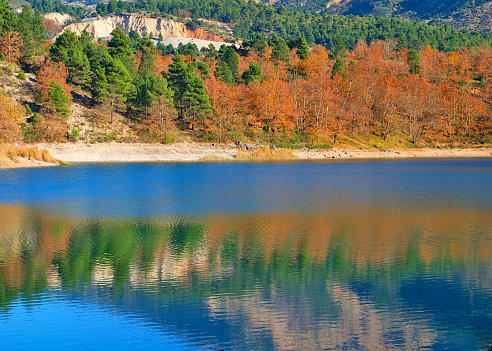 Tsivlou lake at the banks of Helmos mountain in Peloponnese, Greece. Beautiful colorful nature scene of a lake with multicolored trees and their reflections.