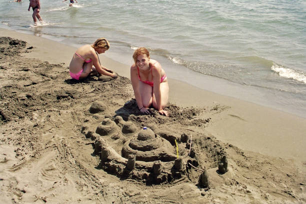 istock Mother and daughter play with sand on a sunny beach 1149153889