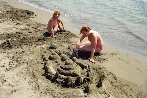 istock Mother and daughter play with sand on a sunny beach 1149153891