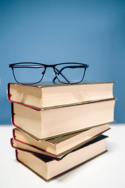 istock Reading glasses and pile stack of books reading and learning concept at home school study 1149153931
