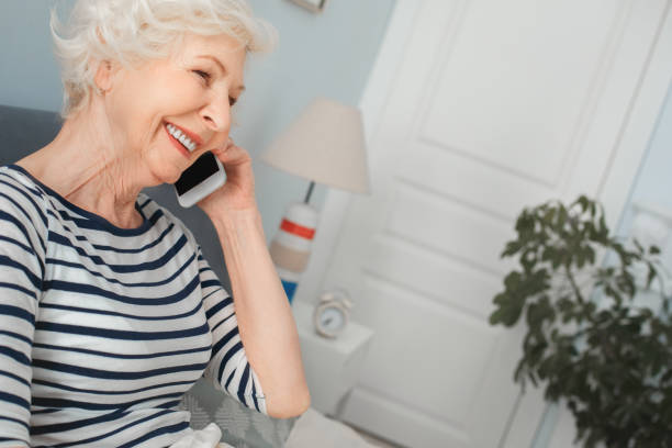 grandma talking to family on the phone in the morning - furniture internet adult blond hair imagens e fotografias de stock