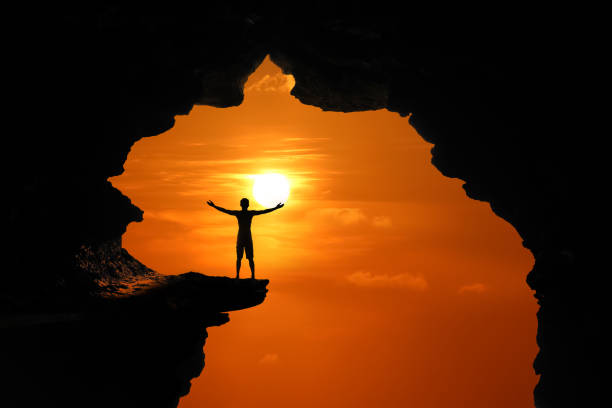 istock The man standing in a cave on a high cliff at red sky sunset 1149160293