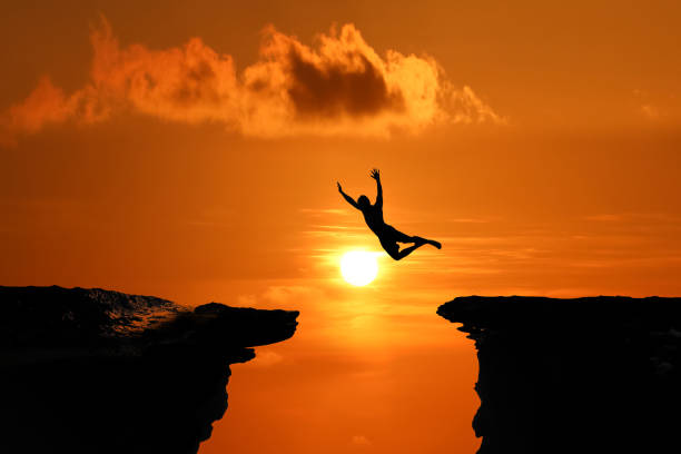 istock Silhouette of Men are jumped between high cliff at a red sky sunset 1149160938