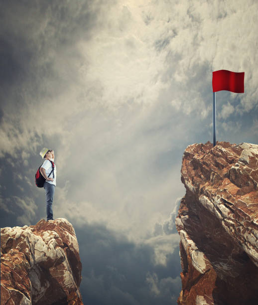 istock Man looking to a red flag over a gap between two mountain peaks. 1149179266